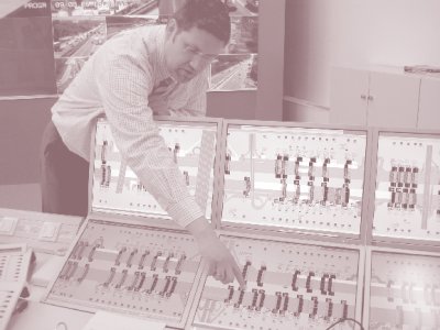 Photo of a man pointing to monitors displaying speed harmonization system information at the Traffic Center Hessen in Germany.