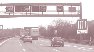 Photo of a gantry with signs indicating right shoulder use with speed harmonization in Germany. The signs indicate speed limits of 100 kilometers per hour in the three driving lanes and the shoulder lane.