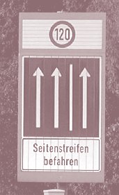 A supplemental 'use hard shoulder' sign includes a speed limit indication, the numeral 120 surrounded by a circle, with the three vertical arrows.