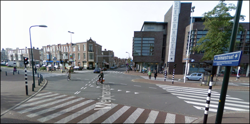 old situation: a signalled intersection - Description: An intersection with street signals and poles on every side of the intersection with cyclists and cars on the same side of the road 